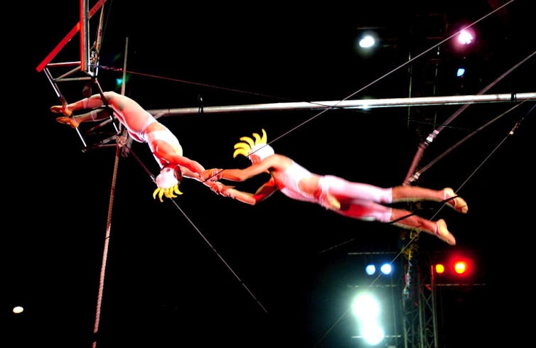 Two trapeze artists dressed like cockatoos.