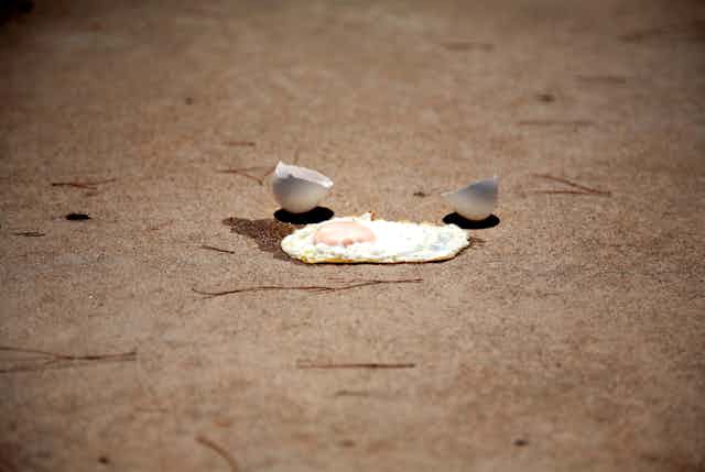 Fried egg and cracked eggshell on concrete