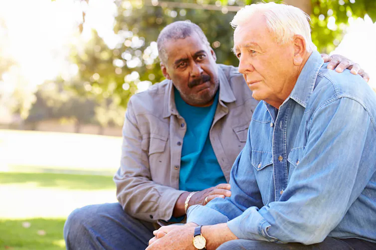 One elderly man comforting another