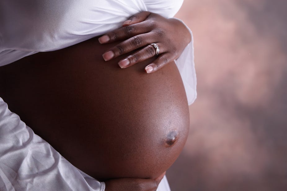 A closeup of a black woman's pregnant belly.