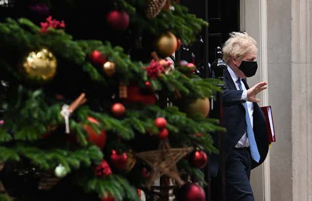 Boris Johnson departs No 10 Downing Street, with a Christmas tree in the foreground.