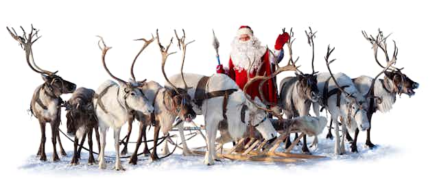 Santa waves behind a line of reindeer.