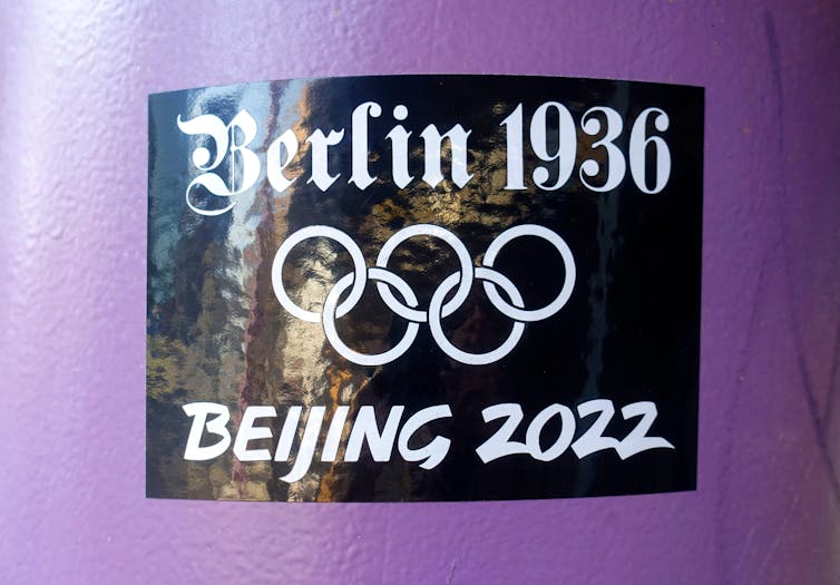 A black sticker with white text showing the Olympic rings, with the text Berlin 1936, Beijing 2022.