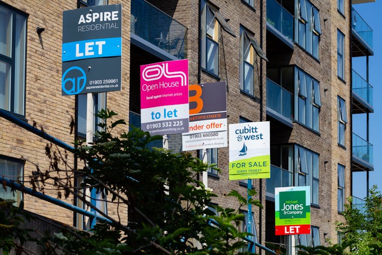 For sale signs are affixed in front of a block of flats.