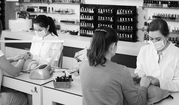 Women sit at a nail salon.