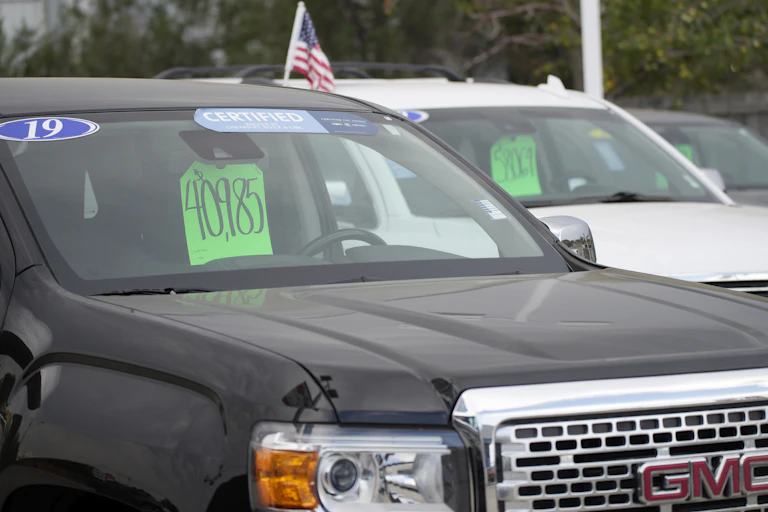 A used 2019 GMC pickup truck sits in a dealer lot with a price tag of $40,985 in the window