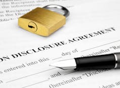A lock is seen on top of a non-disclosure agreement.