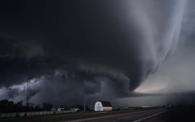 Image of a dark supercell cloud formation above farms