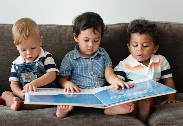 Three kids reading picture book.