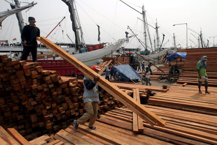 people carry timber at port