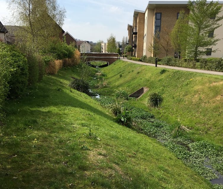 A shallow, green valley with buildings on either side.