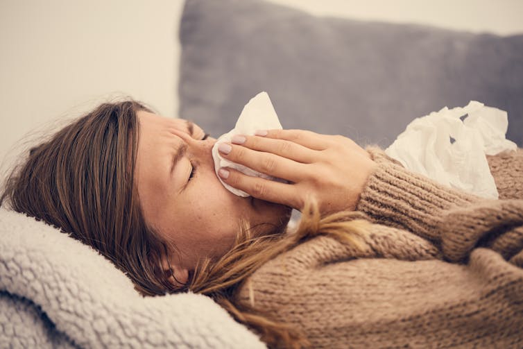 A woman with cold-like symptoms blowing her nose