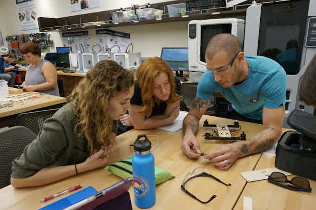 Students and an instructor at lab table look at technology