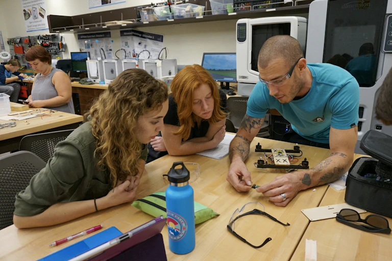 Students and an instructor at lab table look at technology