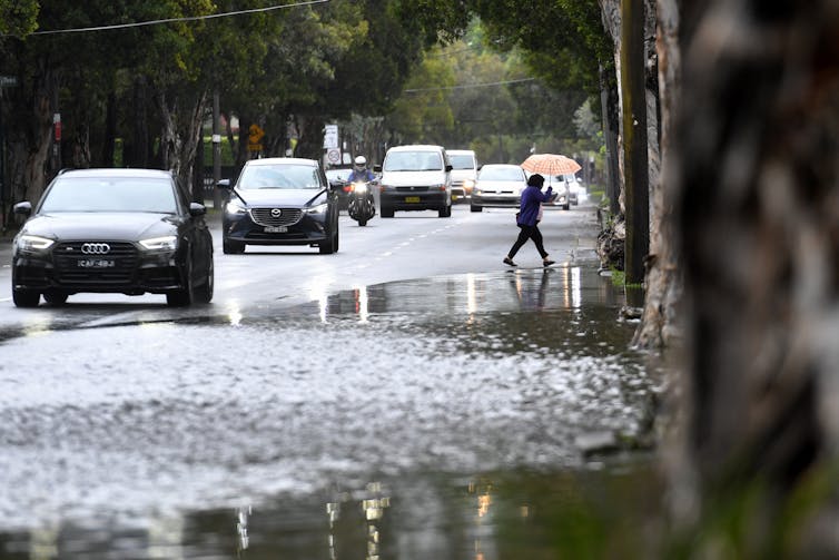 cars and pedestrian traverse wet road