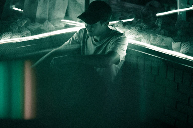Young man in a cap, sits in a room surrounded in windows.