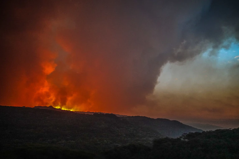 A bushfire in the distance, with billowing smoke.