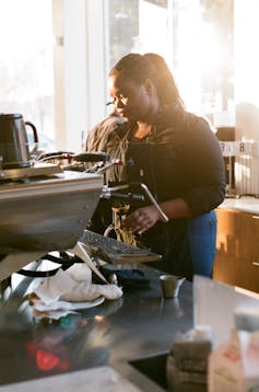 Woman makes coffee at a cafe.