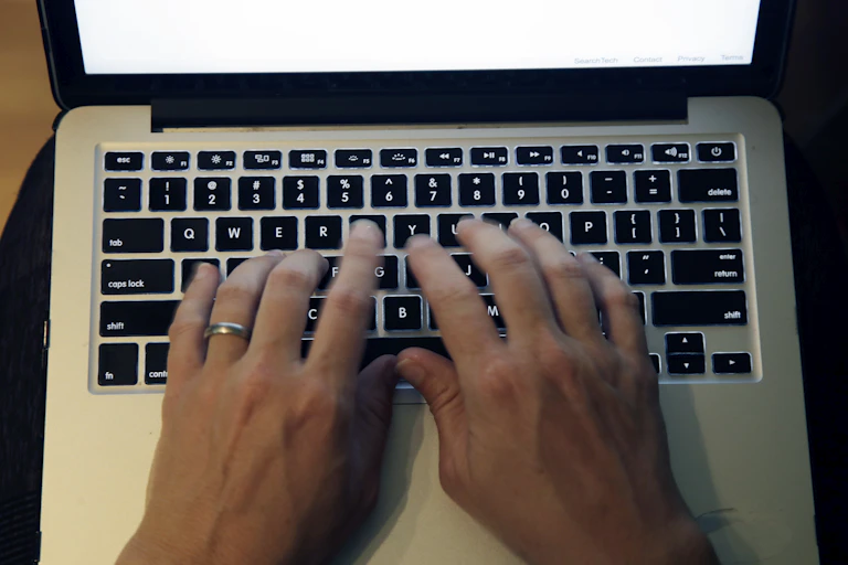 Hands typing on a laptop