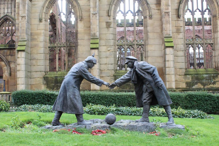 Statute of two soldiers shaking hands over a football.