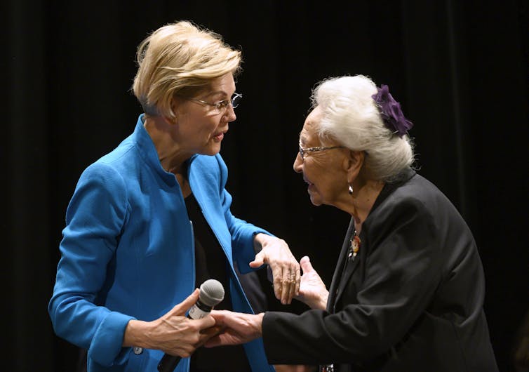U.S. Senator Elizabeth Warren appears to greet an elderly woman, Marcella LeBeau, on a stage