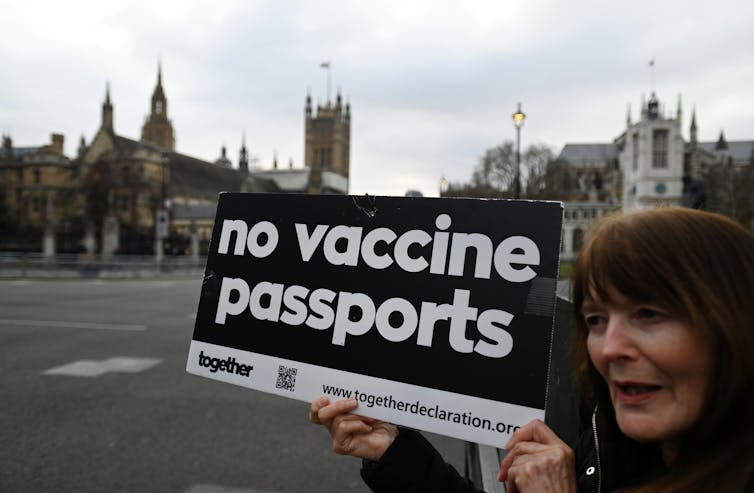 A woman holding up a sign saying 'no vaccine passports'