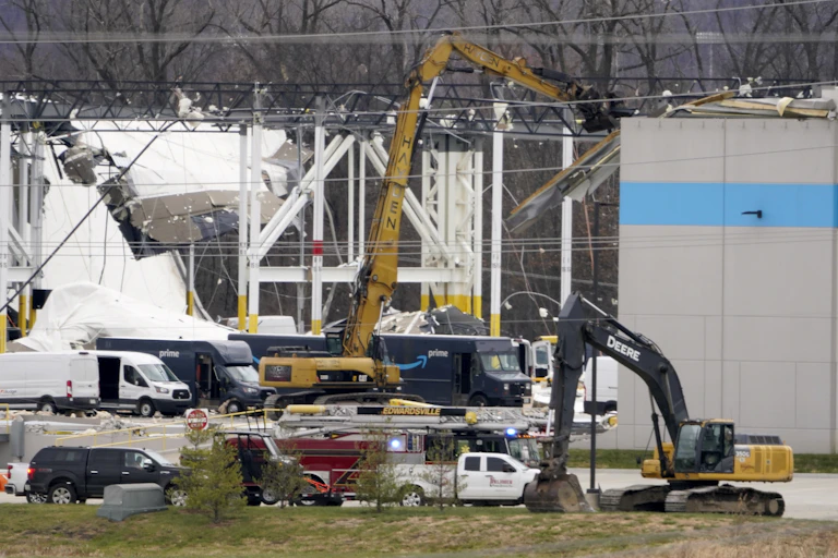 A crane is seen outside a heavily-damaged Amazon fulfillment center.