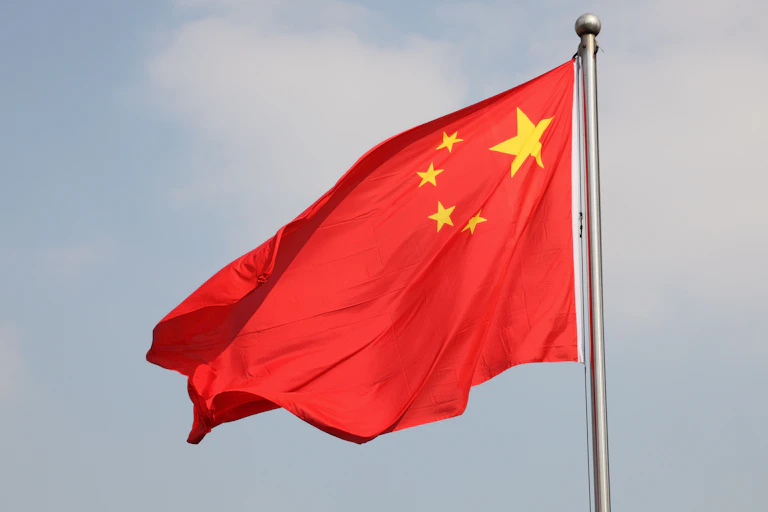 The Chinese flag flutters against a light blue sky.