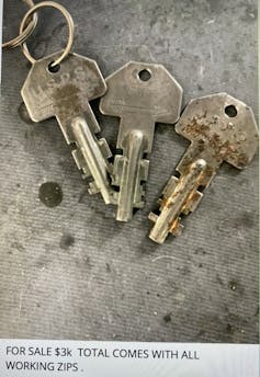 Three USPS mailbox keys lie on a gray surface
