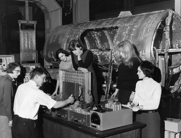 Students in a 1966 black-and-white photo stand around aeronautics equipment