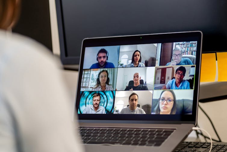 A screen with many faces on it participating in a video conference.