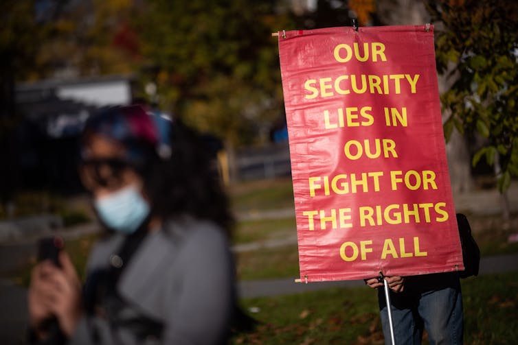 A sign reads 'our security lies in our fight for the rights of all'