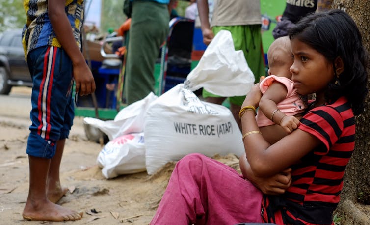 Girl taking care of baby sister at refugee camp in Bangladesh.