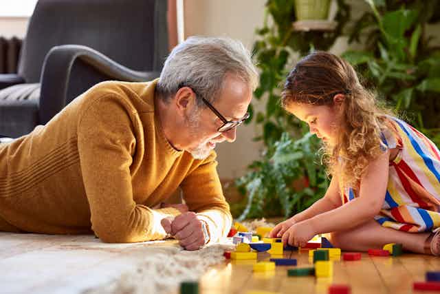 Grandfather playing with building blocks with granddaughter