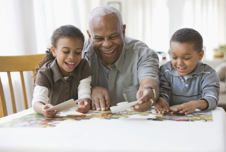 Grandfather doing a jigsaw puzzle with two grandchildren