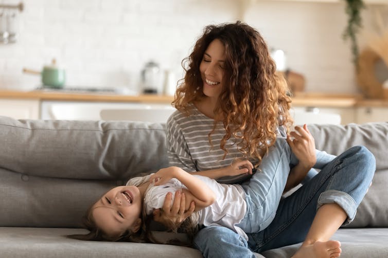 Mother and daughter laughing on the couch.