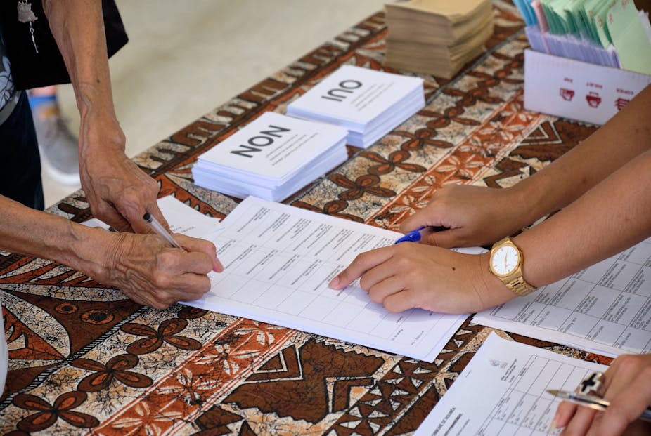 Un homme se prépare à déposer son bulletin de vote pour le référendum sur l'indépendance dans un bureau de vote de l'hôtel de ville de Nouméa, sur le territoire français du Pacifique Sud de la Nouvelle-Calédonie, le 12 décembre 2021.