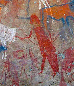 Drawing in red on a rock depicting a figure in a cloak, moving forward, arms extended. Around them cattle and people.