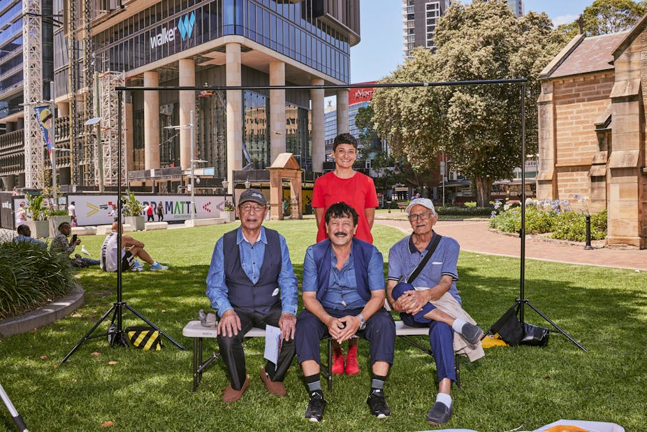 Artist Cherine Fahd stands in a photoshoot with three men in Parramatta City, western Sydney. 