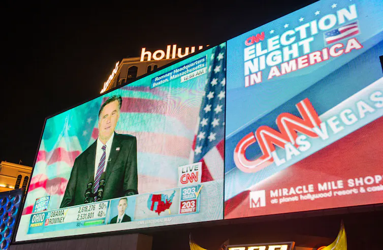 An outdoor screen featuring live coverage of the 2012 US election results.