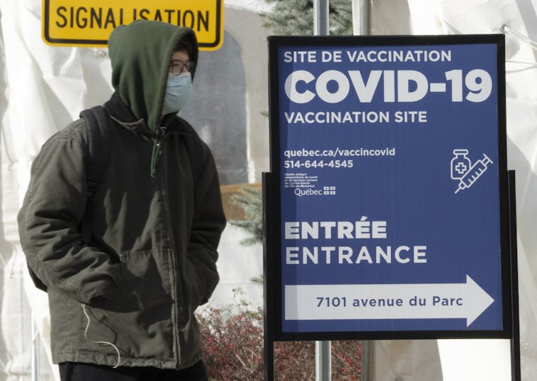 Une personne avec un manteau à capuche entrant dans une clinique de vaccination Covid-19