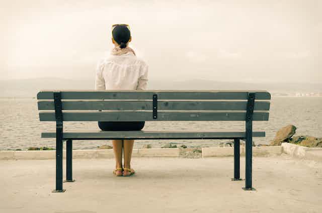 A woman sitting by herself on a bench.