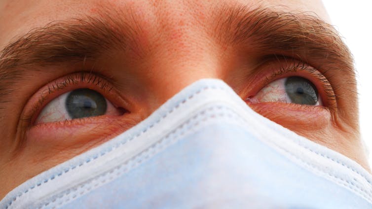 Close up of irritated eyes of a man wearing a protective face mask