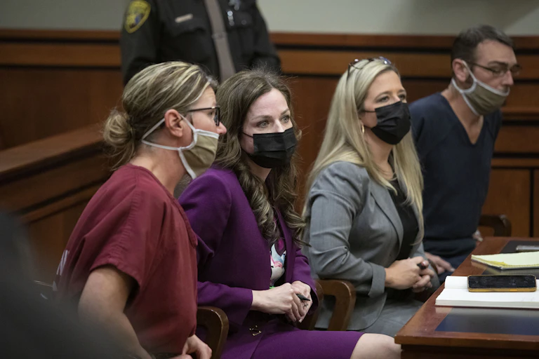 James and Jennifer Crumbley sit with their attorneys at a court desk.