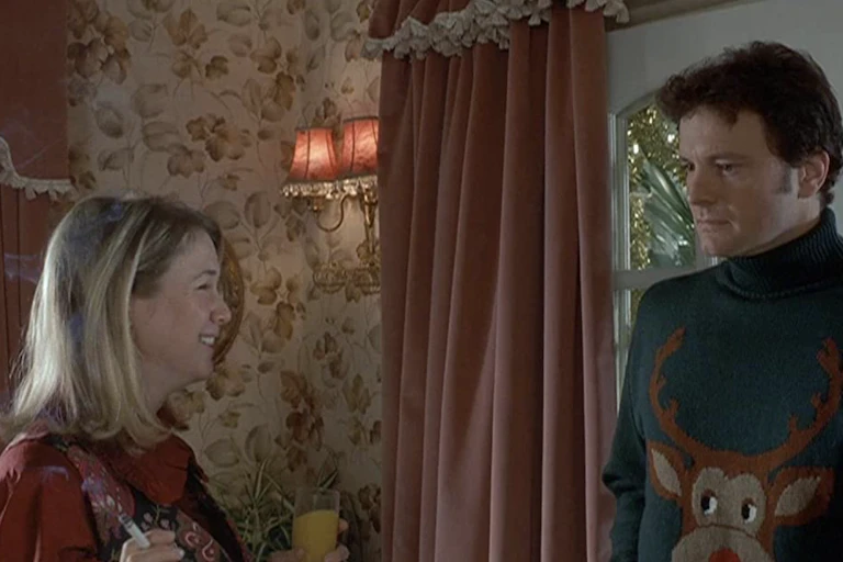 A woman and man stand next to one another wearing ugly Christmas sweaters