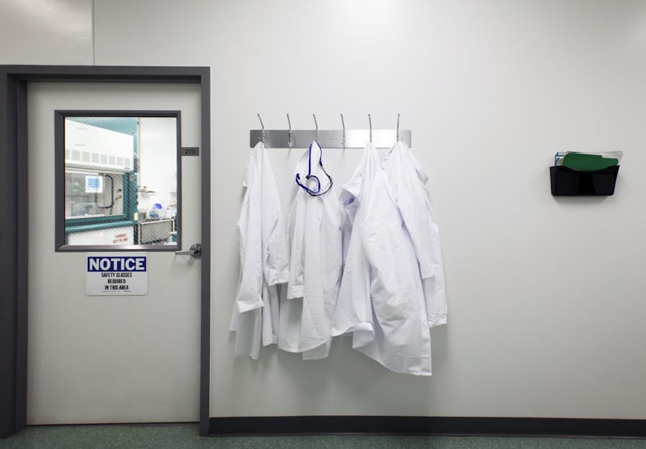 Lab coats hanging on a rack outside of a laboratory.