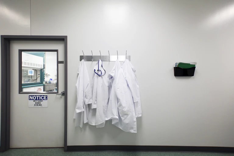 Lab coats hanging on a rack outside of a laboratory.