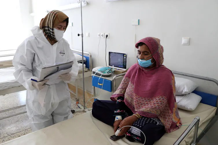 A female doctor treats a woman in an Afghan COVID ward.