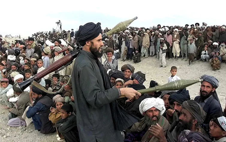 A Taliban fighter armed with rocket-propelled grenades with a group of refugees in near Herat, Afghanistan.