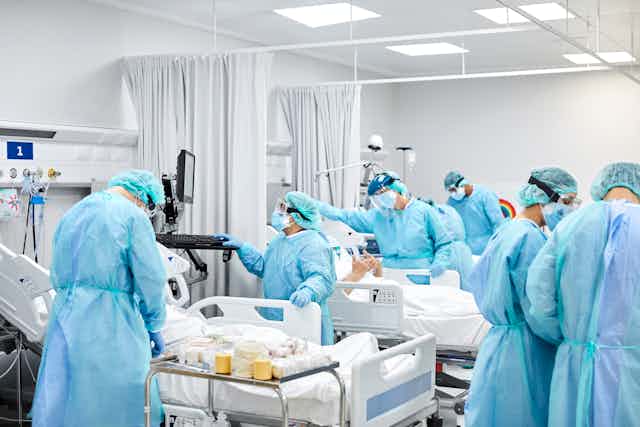 Doctors and nurses in ICU, wearing protective gowns, masks and goggles.